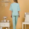 Woman with blond hair wearing turquoise organic cotton pajama set of short sleeve blouse and long pants