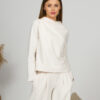 Woman with blond hair wearing organic cotton white blouse with semi-polo neck and white wide long pants