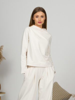 Woman with blond hair wearing organic cotton white blouse with semi-polo neck and white wide long pants