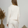 Woman with blond hair wearing organic cotton white blouse with semi-polo neck and white wide long pants