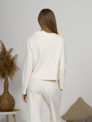 Woman with blond hair wearing organic cotton white blouse with semi-polo neck and white wide long pants