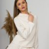 Woman with blond hair wearing organic cotton white blouse with semi-polo neck and white wide long pants