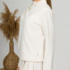Woman with blond hair wearing organic cotton white blouse with semi-polo neck and white wide long pants