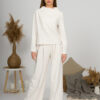 Woman with blond hair wearing organic cotton white blouse with semi-polo neck and white wide long pants
