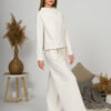 Woman with blond hair wearing organic cotton white blouse with semi-polo neck and white wide long pants