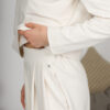 Woman with blond hair wearing organic cotton white blouse with semi-polo neck and white wide long pants