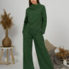 Woman with blond hair wearing organic cotton dark green color blouse with semi-polo neck and white dark green color long pants