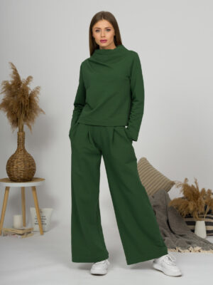Woman with blond hair wearing organic cotton dark green color blouse with semi-polo neck and white dark green color long pants