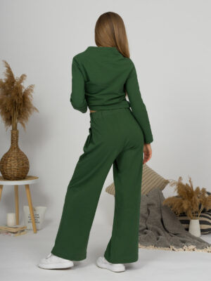 Woman with blond hair wearing organic cotton dark green color blouse with semi-polo neck and white dark green color long pants