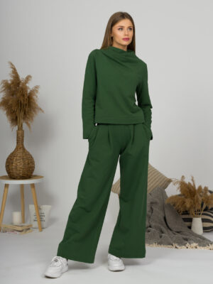 Woman with blond hair wearing organic cotton dark green color blouse with semi-polo neck and white dark green color long pants