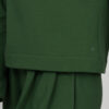 Close view woman with blond hair wearing organic cotton dark green color blouse with semi-polo neck and white dark green color long pants