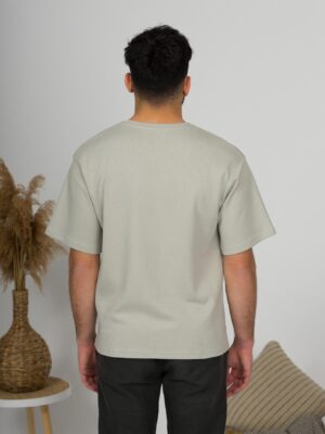 a young man with black hair wearing organic cotton gray t-shirt and black trousers