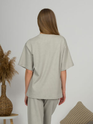 A young woman with blond hair wearing organic cotton gray t-shirt and gray straight leg trousers
