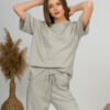 A young woman with blond hair wearing organic cotton gray t-shirt and gray straight leg trousers