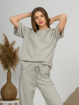 A young woman with blond hair wearing organic cotton gray t-shirt and gray straight leg trousers