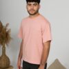 a young man with black hair wearing organic cotton pink t-shirt and black trousers