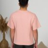 a young man with black hair wearing organic cotton pink t-shirt and black trousers