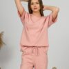 A young woman with blond hair wearing organic cotton pink t-shirt and pink straight leg trousers
