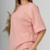 A young woman with blond hair wearing organic cotton pink t-shirt and pink straight leg trousers
