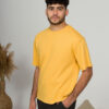 a young man with black hair wearing organic cotton yellow t-shirt and black trousers