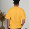 a young man with black hair wearing organic cotton yellow t-shirt and black trousers