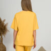 A young woman with blond hair wearing organic cotton yellow t-shirt and yellow straight leg trousers