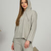 A young woman with blond hair wearing organic cotton hooded blouse and straight leg trousers in gray color