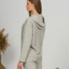 A young woman with blond hair wearing organic cotton hooded blouse and straight leg trousers in gray color