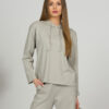 A young woman with blond hair wearing organic cotton hooded blouse and straight leg trousers in gray color