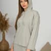 A young woman with blond hair wearing organic cotton hooded blouse and straight leg trousers in gray color