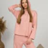 A young woman with blond hair wearing organic cotton hooded blouse and long pants in pink color