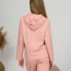 A young woman with blond hair wearing organic cotton hooded blouse and long pants in pink color