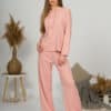 A young woman with blond hair wearing organic cotton hooded blouse and long pants in pink color