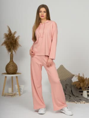A young woman with blond hair wearing organic cotton hooded blouse and long pants in pink color
