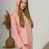 A young woman with blond hair wearing organic cotton hooded blouse and long pants in pink color