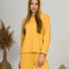 A young woman with blond hair wearing organic cotton hooded blouse and straight leg trousers in yellow color