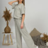 A young woman with blond hair wearing organic cotton t-shirt and straight leg trousers in gray color