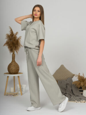 A young woman with blond hair wearing organic cotton t-shirt and straight leg trousers in gray color