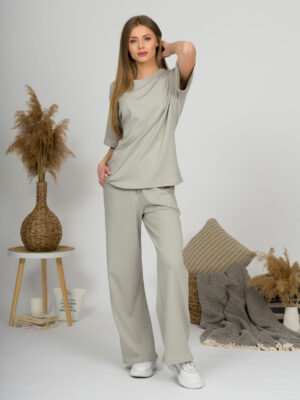 A young woman with blond hair wearing organic cotton t-shirt and straight leg trousers in gray color