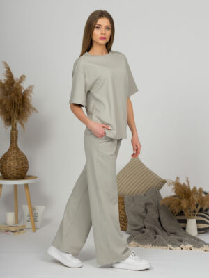 A young woman with blond hair wearing organic cotton t-shirt and straight leg trousers in gray color