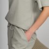 A young woman with blond hair wearing organic cotton t-shirt and straight leg trousers in gray color