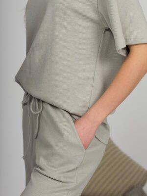 A young woman with blond hair wearing organic cotton t-shirt and straight leg trousers in gray color