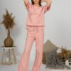 A young woman with blond hair wearing organic cotton t-shirt and straight leg trousers in pink color