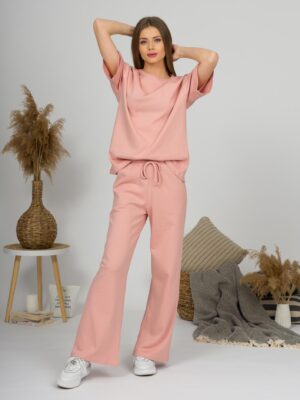 A young woman with blond hair wearing organic cotton t-shirt and straight leg trousers in pink color
