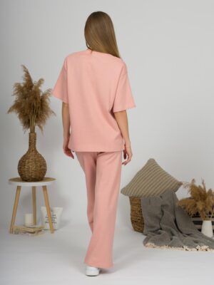 A young woman with blond hair wearing organic cotton t-shirt and straight leg trousers in pink color