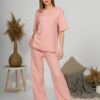 A young woman with blond hair wearing organic cotton t-shirt and straight leg trousers in pink color
