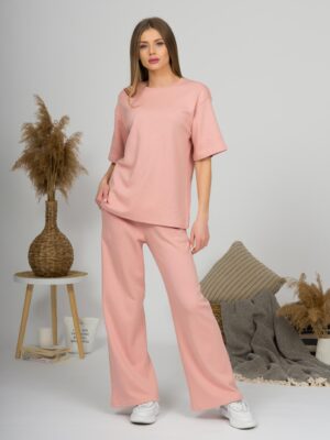 A young woman with blond hair wearing organic cotton t-shirt and straight leg trousers in pink color