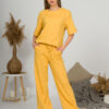 A young woman with blond hair wearing organic cotton yellow t-shirt and yellow straight leg trousers