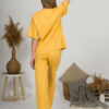 A young woman with blond hair wearing organic cotton yellow t-shirt and yellow straight leg trousers