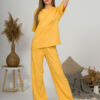A young woman with blond hair wearing organic cotton yellow t-shirt and yellow straight leg trousers